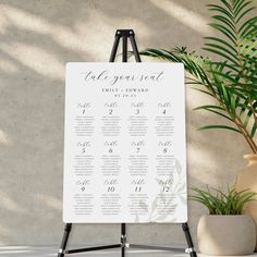 a white table plan sitting next to a potted plant