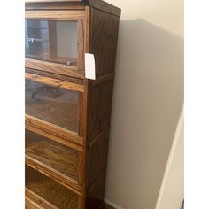 a wooden cabinet sitting next to a wall with a white tag on it's door