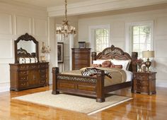 a bedroom scene with focus on the bed, dressers and mirror in the room