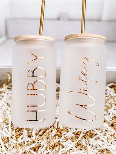 two white glass jars with gold lettering on them