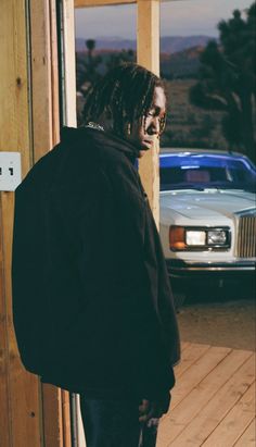 a man with dreadlocks standing in front of a door