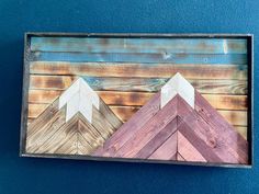 three wooden mountains painted on top of each other in different colors and sizes with wood planks