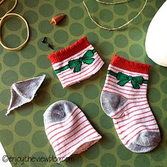 two pairs of socks with green leaves on them sitting next to scissors and yarns