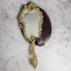 an ornate mirror on the wall with a purple leather case