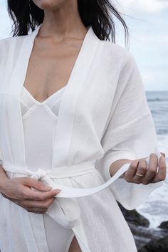 The Bali Robe, inspired by our founders' first trip to Bali, embodies our "bedroom to beach" concept. Crafted from lightweight fabric with a captivating texture reminiscent of rippled water. This versatile robe transitions seamlessly from home attire to beach cover-up, becoming a staple in your daily wardrobe. Drop Sleeve Relaxed fit Semi-sheer Midi length Tie waist belt Pockets Elegant Summer Robe For Relaxation, Elegant Summer Relaxation Kimono, Linen Robe For Beach In Summer, Summer Wrap Robe For Lounging, Summer Beach Linen Robe, Summer Lounging Wrap Robe, Summer Relaxation Robe With Kimono Sleeves, Summer Linen Robe For Relaxation, Summer Wrap Robe For Relaxation