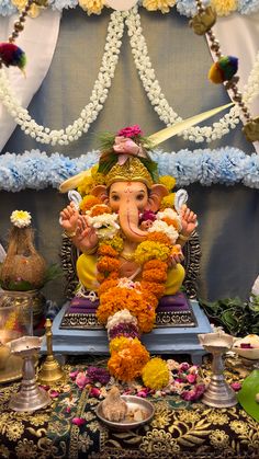 an elephant statue sitting on top of a table covered in flowers and garlands next to other decorations