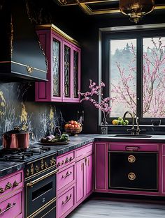 a kitchen with pink cabinets and black counter tops, along with an open window that looks out onto the outside