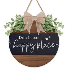 this is our happy place sign hanging on a door hanger with a bow and greenery