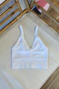 Ribbed v-neck bra top with thick hems. 92% Nylon 8% Spandex | Hand wash cold One size Made in USA White Seamless V-neck Top, Seamless V-neck Stretch Sports Bra, Seamless V-neck Sports Bra, White Seamless V-neck Crop Top, Stretch V-neck Sports Bra With Seamless Construction, Solid V-neck Sports Bra, Spring V-neck High Stretch Crop Top, Fitted V-neck Seamless Crop Top, White Bra-friendly Low-cut Top