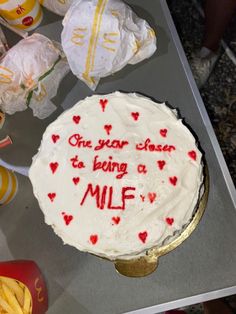 a cake with writing on it sitting on a table next to other plates and cups