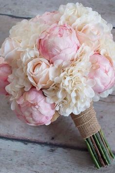 three pink flowers laying on top of a white bed next to green leaves and branches