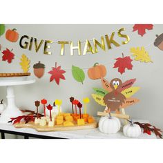 a table topped with lots of food and fall themed decorations next to a sign that says give thanks