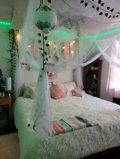 a bed with white sheets and lights on the headboard is in a room that has green lighting