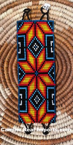 the beaded phone case is hanging on a wicker basket with an orange and blue design