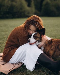 a woman laying in the grass with her dog