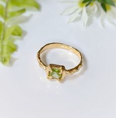 Show your love with this exquisite Peridot ring. Handcrafted in wax and cast in Solid 14k Gold, this stunning green crystal ring features an organic textured band, ensuring its uniqueness. Adorned with a mesmerizing princess-cut Peridot, also the August birthstone, it embodies more than an engagement ring - it symbolizes timeless love and individualityT H E ∙ S M A L L ∙ D E T A I L S• Princess-cut Peridot (5 x 5mm)• Solid 14k Gold textured bandM A T E R I A L ∙ O P T I O N S• Sterling Silver• S Nature-inspired Yellow Gold Gemstone Rings, 14k Gold Green Crystal Ring With Ethical Gemstones, Green Crystal Ring In 14k Gold, Green 14k Gold Crystal Ring Fine Jewelry, Green Birthstone Jewelry In Recycled Gold, Green Peridot Promise Jewelry, Green Peridot Jewelry For Promise, Green Recycled Gold Jewelry For May Birthstone, Hand Forged Yellow Gold Nature-inspired Rings