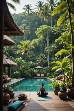 a person sitting on a mat in front of a pool surrounded by trees and plants