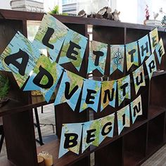 there is a sign that says adventure on the side of a book shelf with flags hanging from it