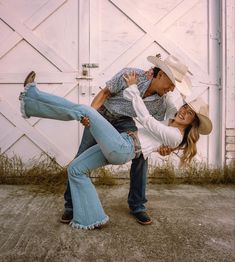 a man and woman are dancing in front of a barn door with their arms around each other