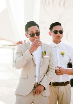 two men in suits and sunglasses standing next to each other with their hands on their chins