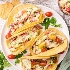 fish tacos with citrus salsa on a white plate surrounded by tortilla chips