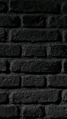 black and white photograph of brick wall with light coming from the top, dark background