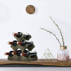 a wooden shelf with several wine bottles on it and a small vase next to it