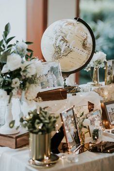 a table topped with pictures and vases filled with flowers next to a globe on top of a table