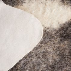 a close up view of an area rug with white and grey fur on it's surface