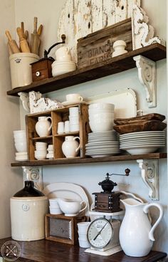 a shelf filled with lots of white dishes and other kitchen ware on top of a wooden table