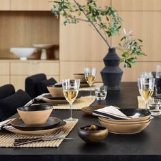 a dining table set for two with wine glasses, plates and utensils