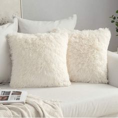 two white pillows sitting on top of a bed next to a pillow with a magazine