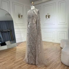 a dress on display in a room with white walls and wood flooring, along with a mirror