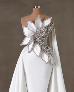 the back of a white wedding dress with an elaborate flower on it