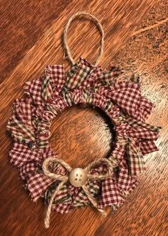 a christmas wreath on a wooden table with burlocked ribbon around it and an ornament hanging from the front