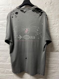 an old t - shirt hanging on a white brick wall with holes and paint splattered all over it