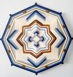 a circular object made out of different colors and shapes on a white wall with blue trim