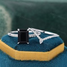 a black diamond ring sitting on top of a blue cushion