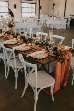 the tables are set with white chairs and orange napkins for an elegant wedding reception