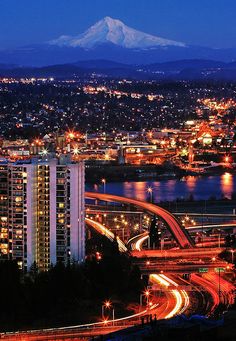 the city lights shine brightly at night in front of a mountain