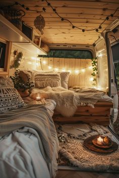 the interior of a camper van decorated with lights, blankets and rugs on the floor