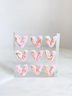 pink and gold hearts in a clear acrylic display case on a white surface