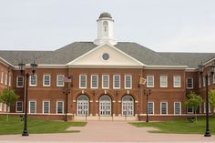 an old brick building with a clock tower on the top and two flags flying in front