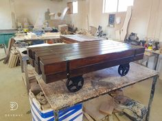 a wooden table with wheels on it in a room full of other furniture and tools