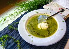 a white bowl filled with green soup on top of a blue place mat next to a napkin