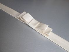 "This elegant simple bridal belt is beautifully made in silk Duchess satin. This belt features an elegant bow in the front and it is finished with the matching buttons and hand crochet loops in the back. This belt measures 1\" wide and the length is finished to your measurements. Available in a variety of colors. * Please include your waist measurements in the notes during checkout and your belt will be finished at that length - For the photos of the color choices please take a look at the listi Elegant Bridal Accessories With Satin Bow, Elegant Cream Bow For Parties, Elegant Cream Bow For Party, Elegant Adjustable Sash For Formal Occasions, Elegant Adjustable Sashes For Formal Occasions, Elegant Formal Adjustable Sash, Elegant Cream Bow With Ribbon Detail, Elegant Satin Bridal Accessories For Wedding, Elegant Formal Adjustable Sashes