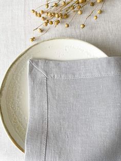 a white plate topped with a piece of cloth next to a dried plant on top of a table