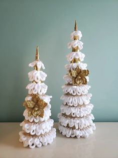 two white and gold decorated christmas trees sitting on top of a table next to each other