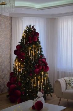 a living room with a christmas tree decorated in red and gold balls, lights and curtains