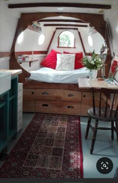 a bed sitting in the middle of a room next to a table and chair with a rug on top of it